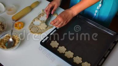 小饼干的准备。 女人正在烤盘上铺上饼干的底座，上面撒着芝麻